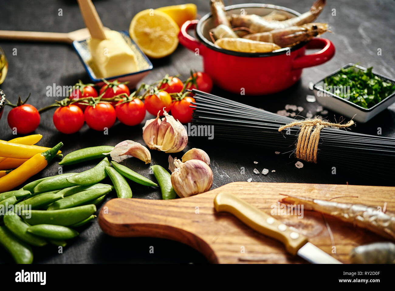 Frische und köstliche rohe Riesengarnelen in einem roten Topf mit Petersilie, Zitrone, Butter, Tomaten und Peperoni Stockfoto
