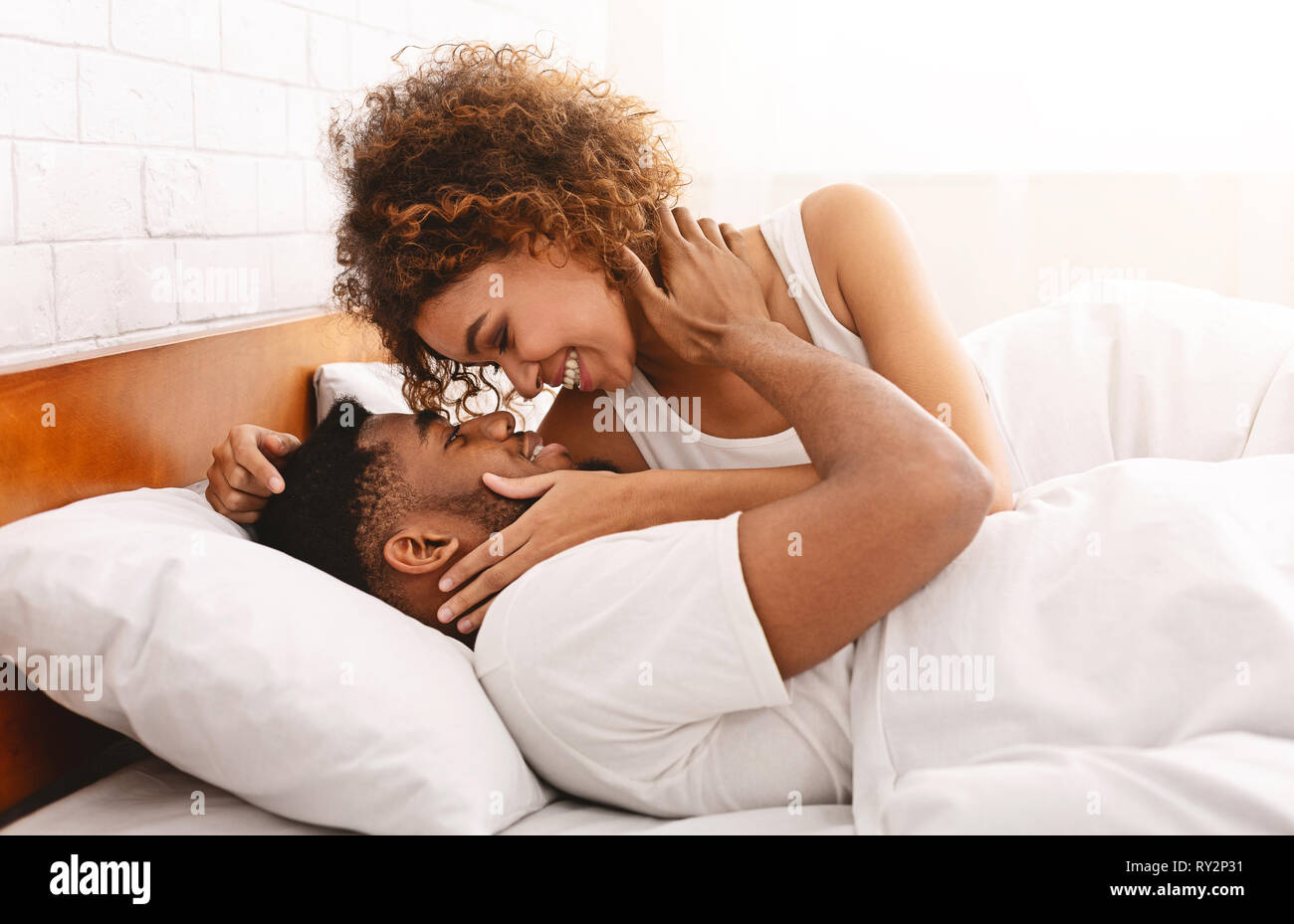 African-American Girl kissing Ihren liebsten im Bett Stockfoto