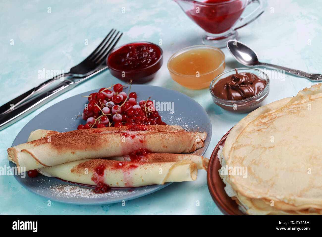 Pfannkuchen mit Beeren, Marmelade, Honig und Schokolade, bestreut mit Puderzucker und Zimt Stockfoto