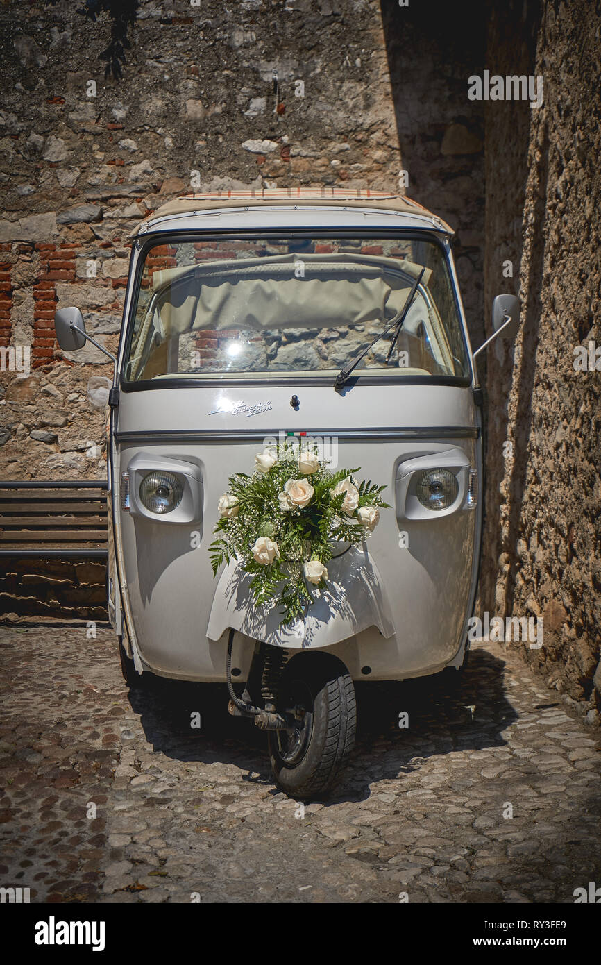 Malcesine, Italien - August, 2018. Ein vintage Piaggio Ape Calessino für eine Hochzeit mit weißen Rosen Blumenstrauß eingerichtet. Stockfoto