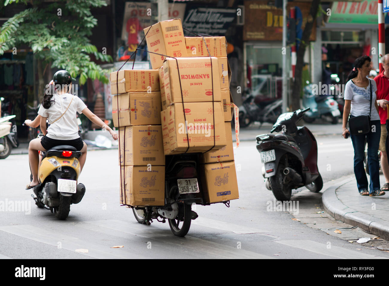 Man Kisten für die Lieferung auf einem Motorrad in einer Straße von Hanoi. Vietnamesische Volk werden verwendet, um zu laden und zu transportieren, eine Menge Sachen auf dem Motorrad. Stockfoto