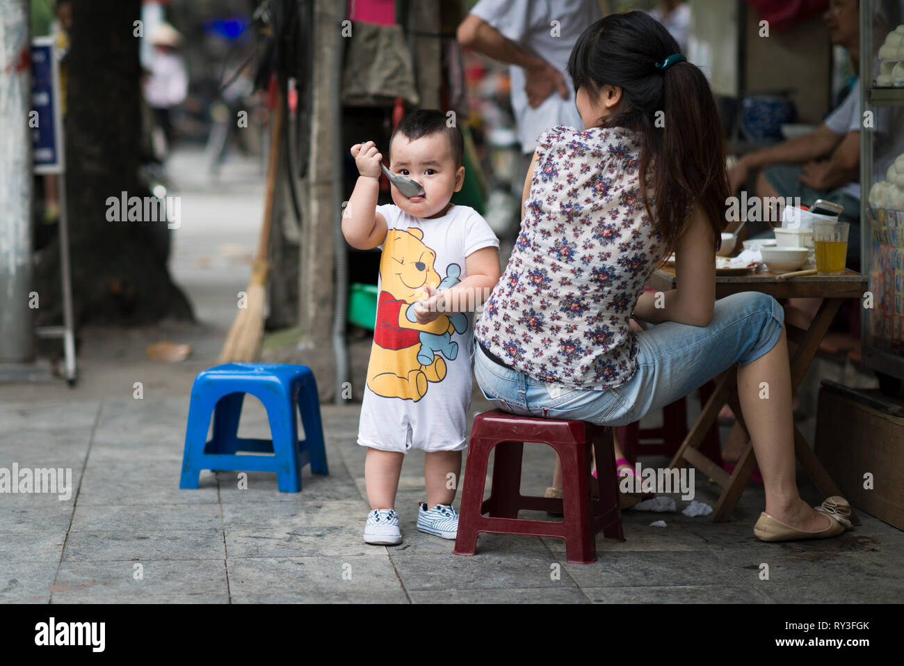 Ein schüchternes und gierig Vietnamesisches Kind Essen auf der Straße, Hanoi Vietnam Stockfoto