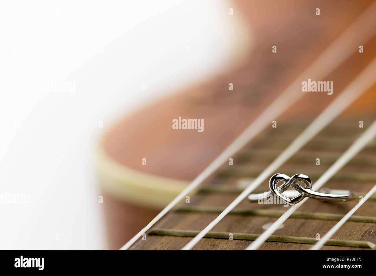 Herzförmigen ring Verlegung auf ukulele String. Das Konzept eines Musikers Liebhaber. Kopieren Raum kann verwendet werden, um Artikel über den Valentinstag zu schreiben. Stockfoto
