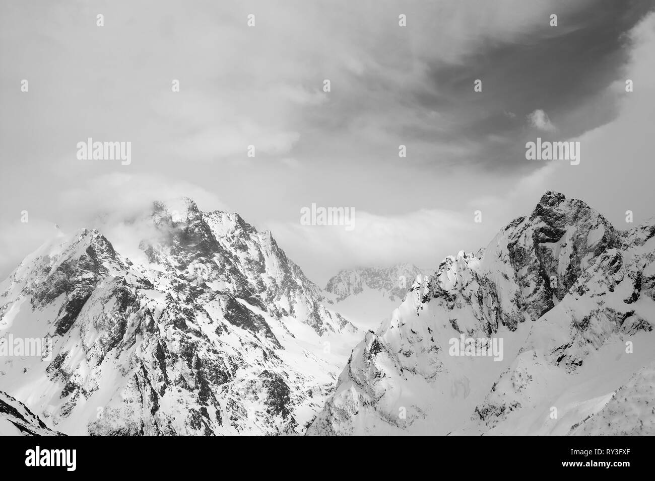 Hohe Berge mit Schnee und Himmel mit Wolken im Winter Tag abgedeckt. Kaukasus, Region Dombay. Schwarz und Weiß getönten Landschaft. Stockfoto