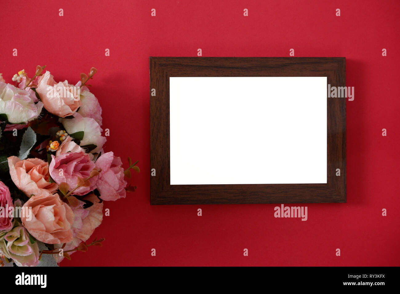 Mock-up Holz Bilderrahmen mit Platz für Bild oder Text auf rotem Hintergrund und Blume Stockfoto
