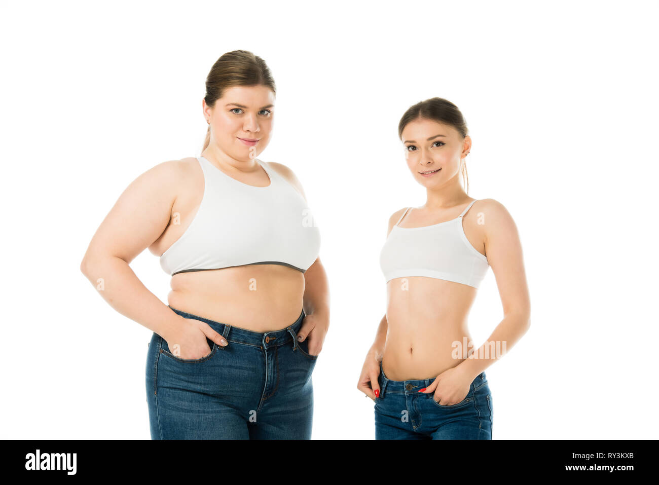 Lächelnd Übergewicht und schlanke Frauen mit Händen in den Taschen auf Weiß, Körper Positivität Konzept isoliert Posing Stockfoto