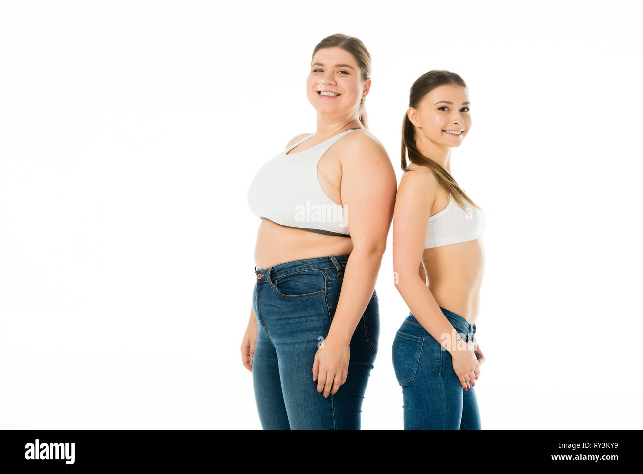 Lächelnd schlank und übergewichtige Frauen in Jeans zusammen auf Weiß, Körper Positivität Konzept isoliert Posing Stockfoto