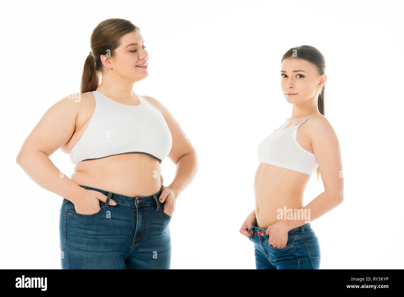 Schlank und übergewichtige Frauen in Jeans mit Händen in den Taschen zusammen auf Weiß, Körper Positivität Konzept isoliert Posing Stockfoto