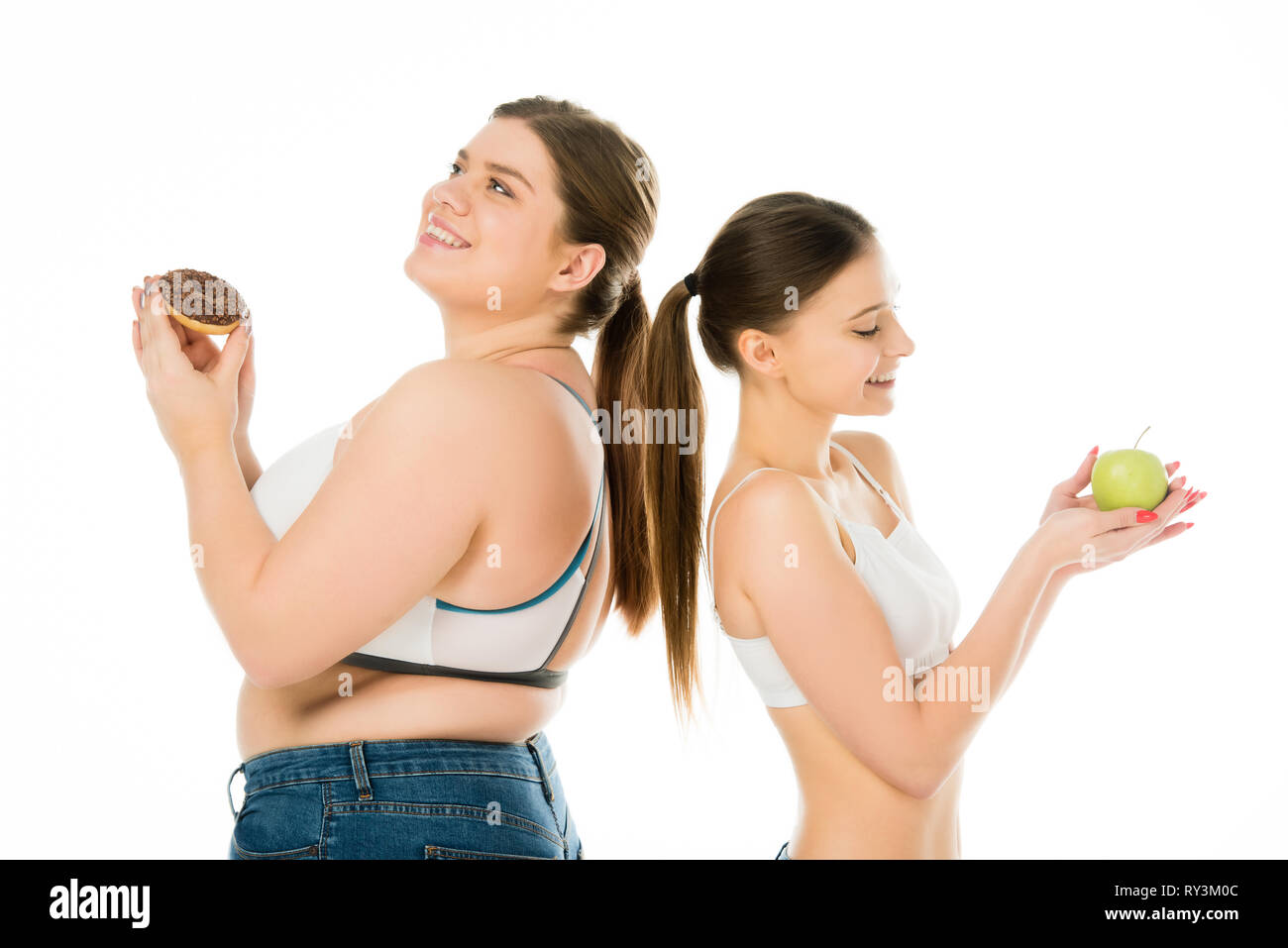 Gerne schlank und übergewichtige Mädchen rücken zusammen mit Donut und Green Apple isoliert auf weißem zurück Stockfoto