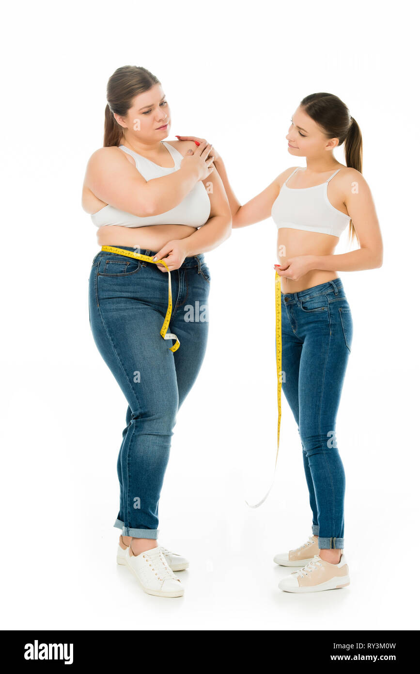 Schlanke Frau die traurige übergewichtige Frau mit Maßband isoliert auf weißem Stockfoto