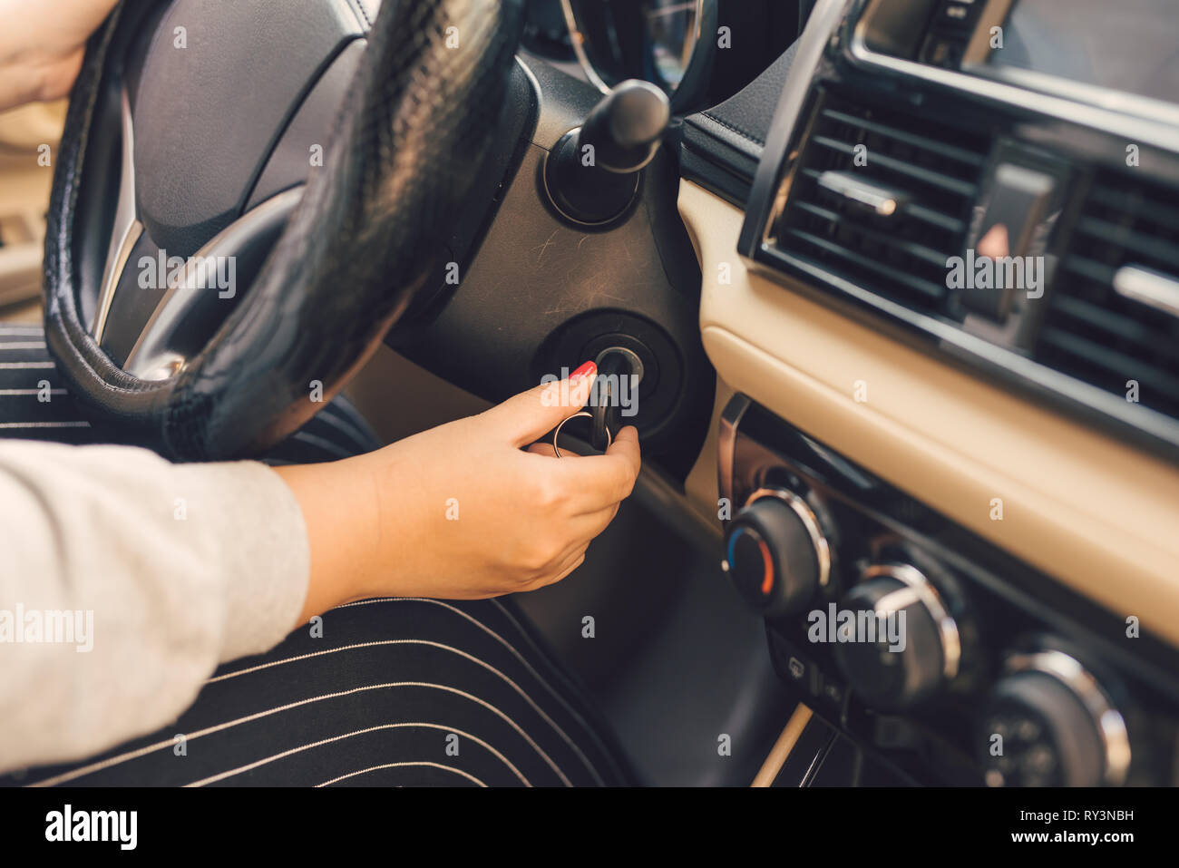 Frau hand Schlüssel in das Zündschloss und startet den Motor Stockfoto