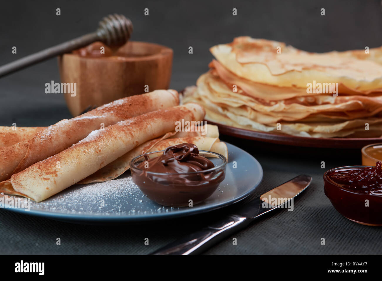 Pfannkuchen mit Beeren, Marmelade, Honig und Schokolade, bestreut mit Puderzucker und Zimt Stockfoto