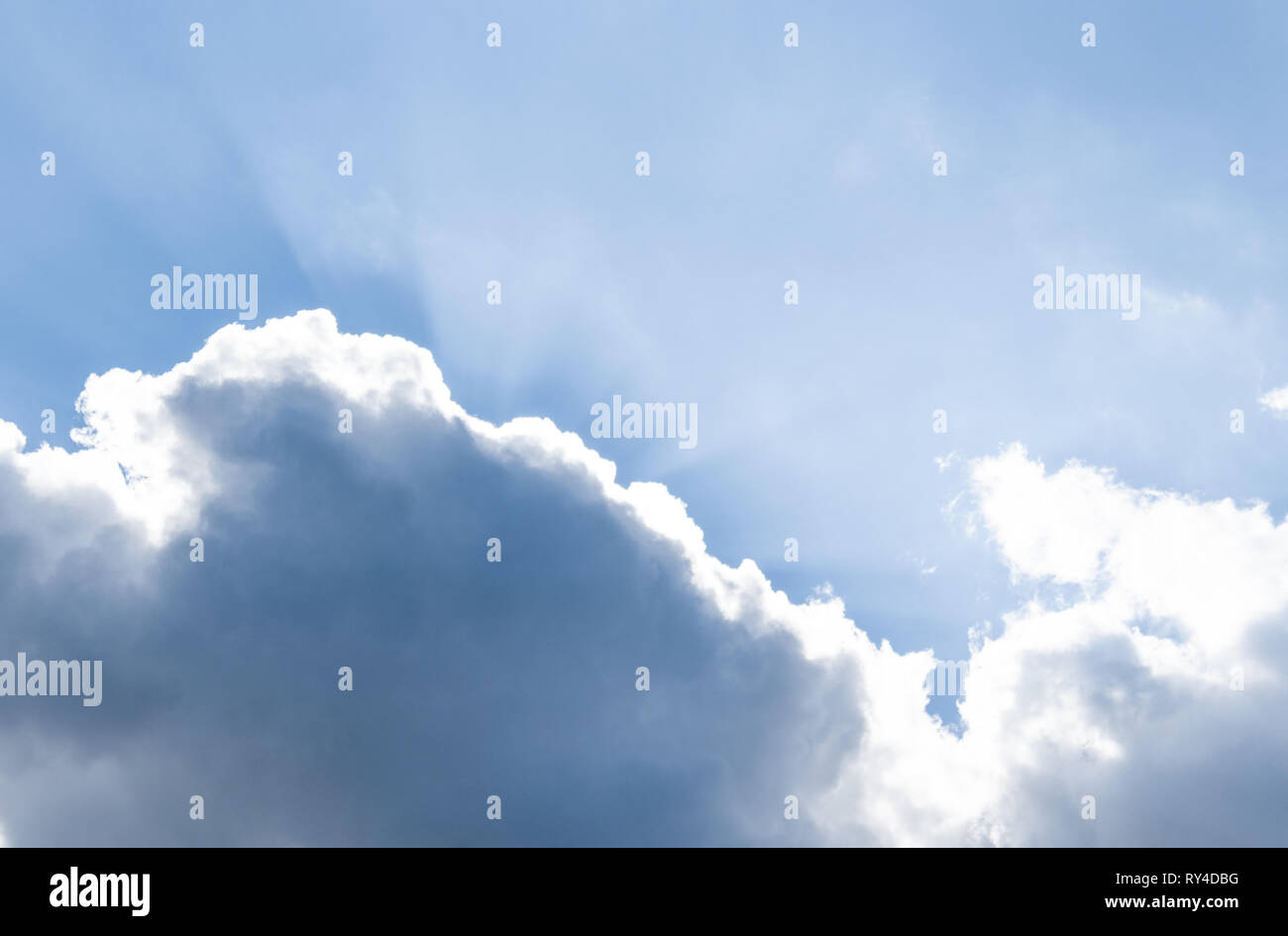 Die Strahlen der Sonne hinter den Wolken im blauen Himmel. Stockfoto
