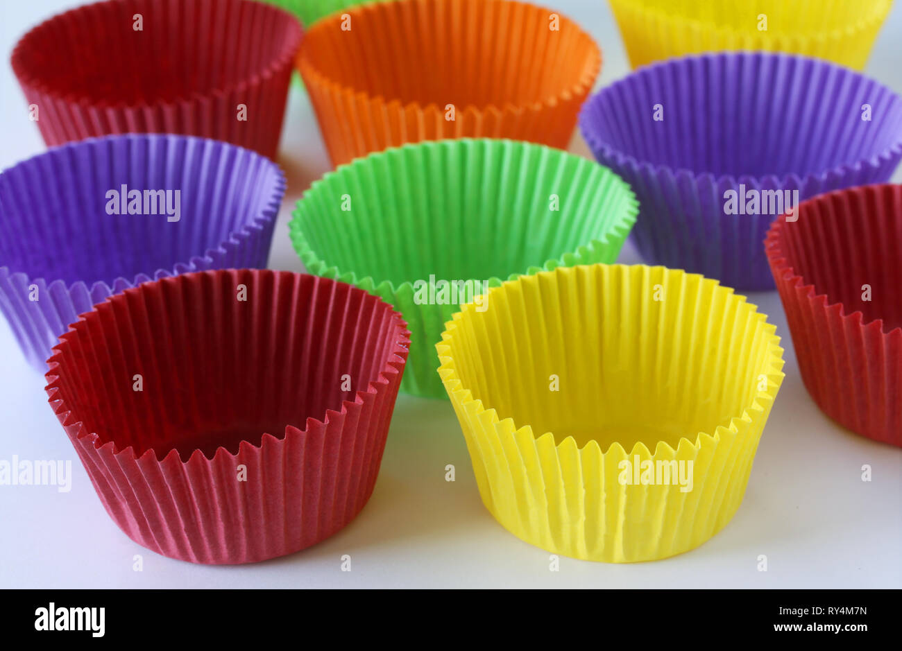 Bunte leere Formen Kapseln für Muffins und Cupcakes auf weißem Hintergrund - Backen Dessert - close up auf weißem Hintergrund Stockfoto