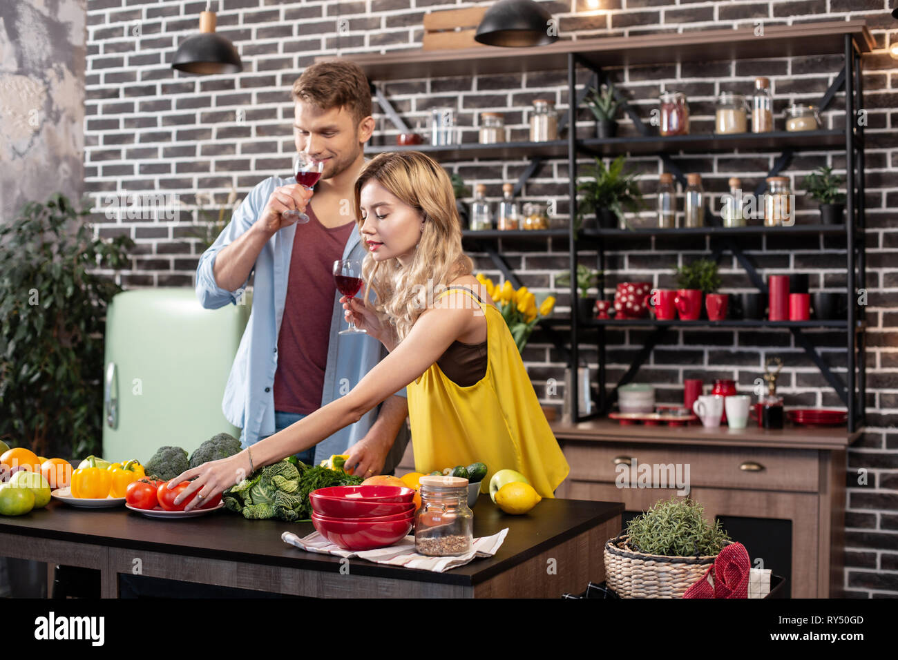 Freundin Schneiden von Gemüse für Salat, Wein trinken und mit ihrem Mann Stockfoto