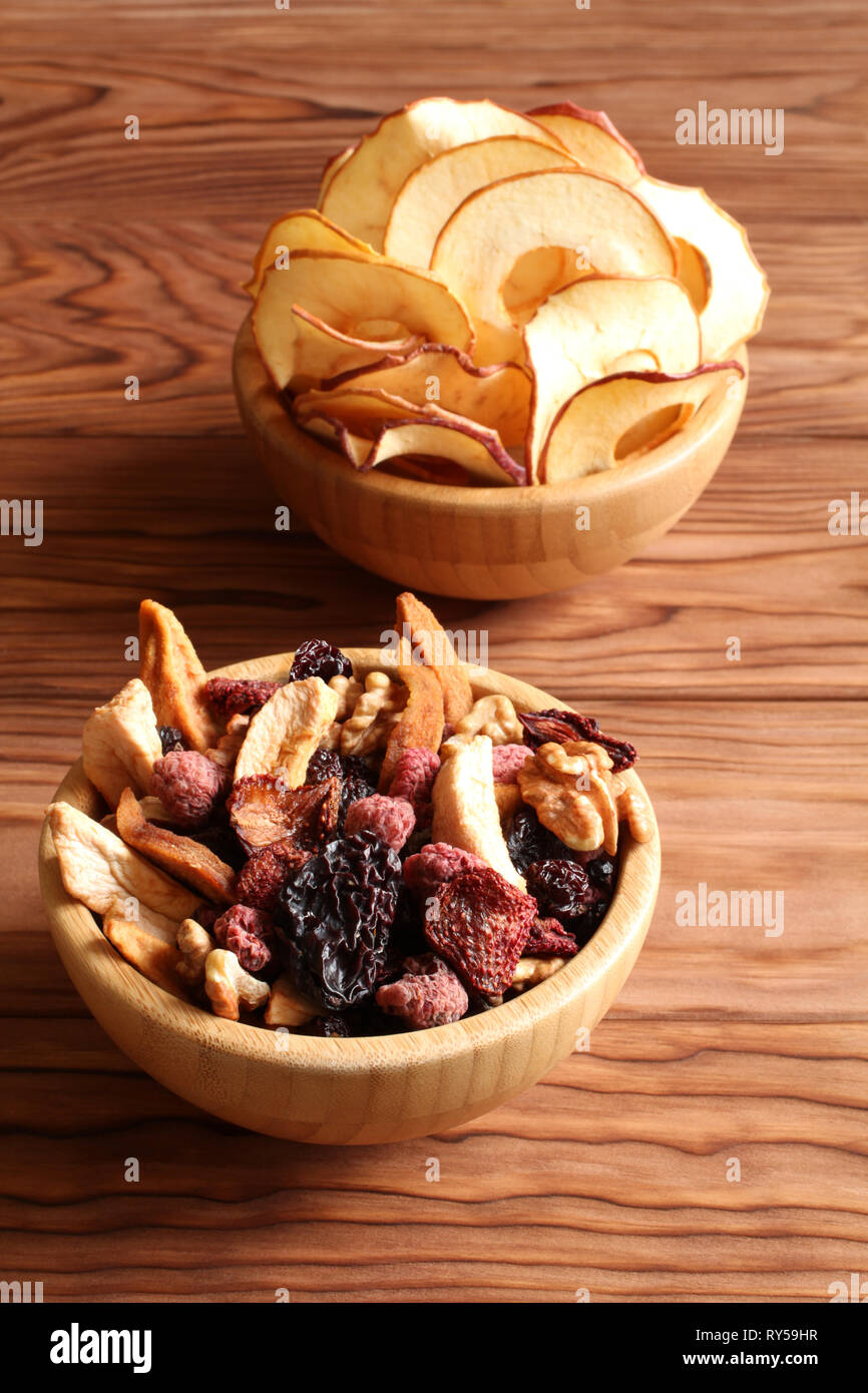 Mischung aus getrockneten Früchten Stücke von Apfel und Birne, getrocknete blaue Pflaumen, Erdbeeren, Himbeeren, Kirschen, Walnüsse in eine Schüssel, und Bambus apple Chips in einem Stockfoto