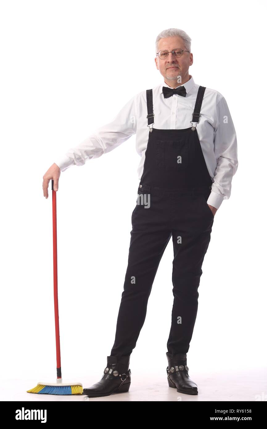 Grauhaarige Reiniger, Hausmeister in einem schwarzen Overall mit einem Mopp und Schaufel bietet Reinigung, auf weißem Hintergrund Stockfoto