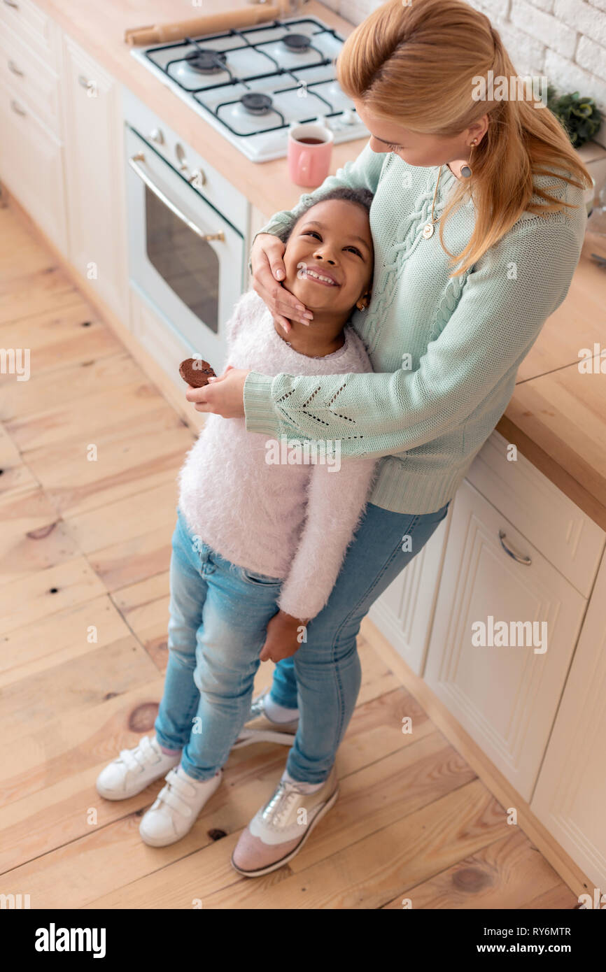 Liebevolle blonde Mutter ihr süßes kleines Mädchen umarmt Stockfoto