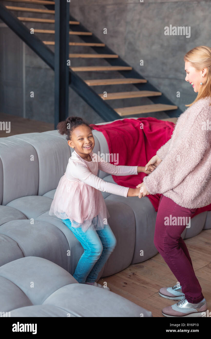 Strahlende Mädchen lachen beim Tanzen mit ihren liebevollen Mom Stockfoto