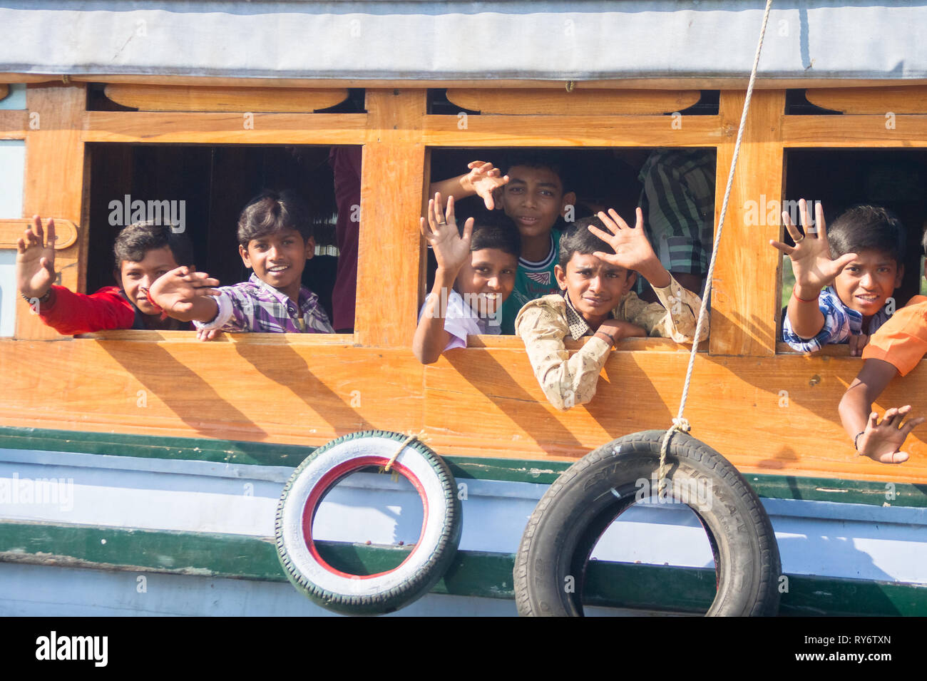 Junge indische Schüler Jungen lächelnd und winkend vom Boot Windows auf Kerala Backwaters, New Delhi, Indien Stockfoto