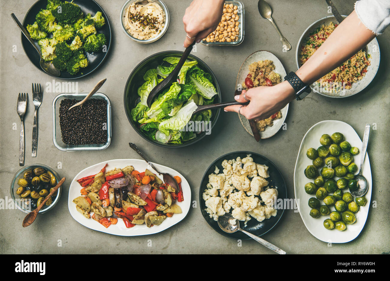 Gesunde vegetarische Gerichte in Platten und Frau Hände unter Salat Stockfoto