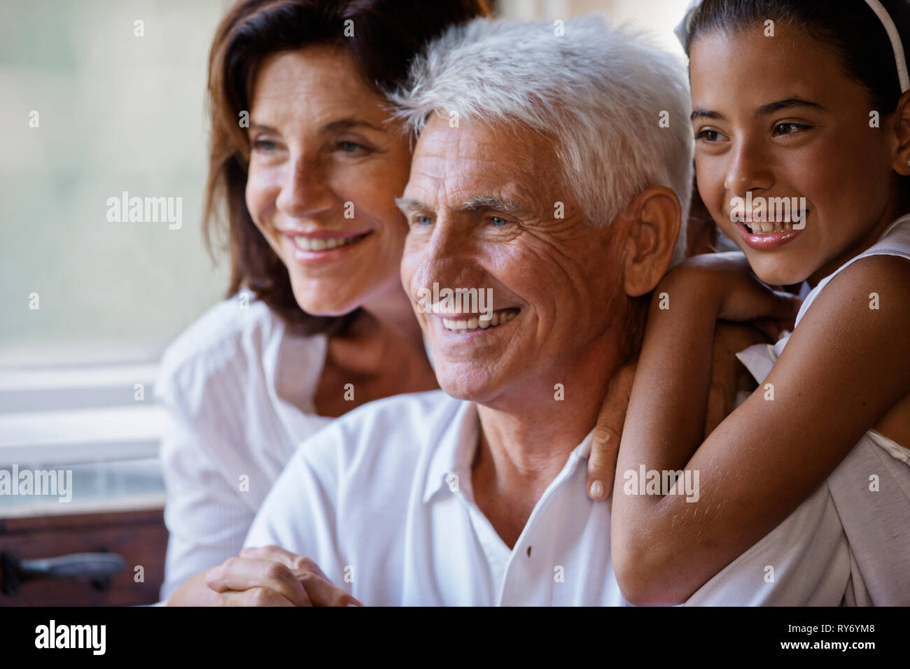 Mädchen glücklich sitzen mit ihren Großeltern, stützte sich auf die Schulter ihres Großvaters. Stockfoto