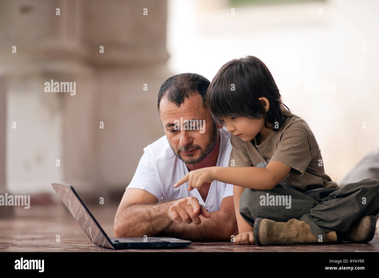 Mitte nach Vater und seinem jungen Sohn in diesem Notebook auf einen gefliesten Terrasse. Stockfoto