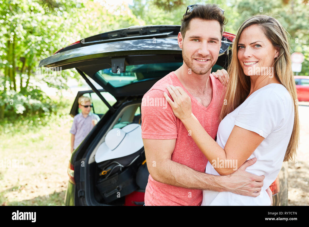 Glückliche Eltern Paar steht vor dem Auto und freuen uns auf die Sommerferien Stockfoto