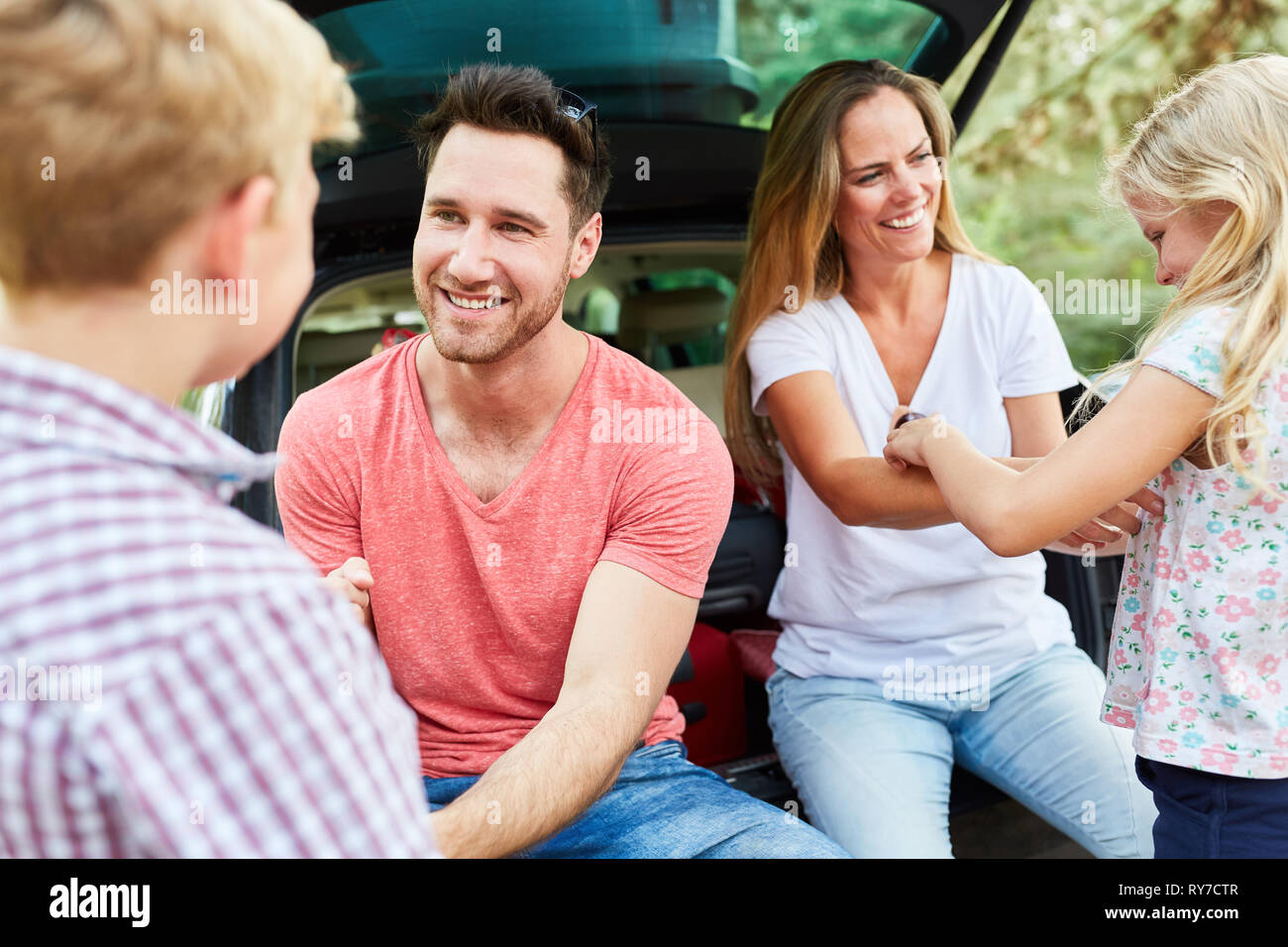 Glückliche Eltern im Auto auf einer Reise in den Urlaub mit zwei Kindern Stockfoto