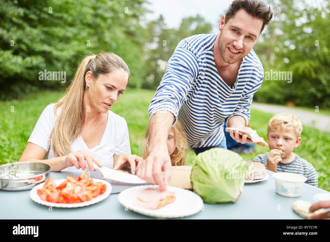 Familie mit Kindern zusammen essen im Garten oder auf dem Campingplatz Stockfoto