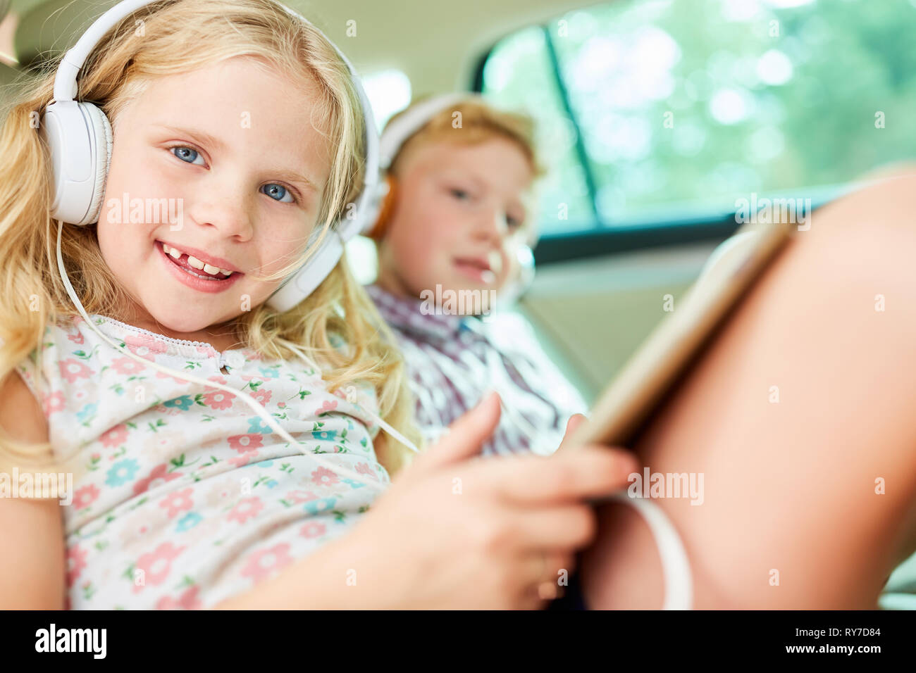 Geschwister Kinder im Auto Musik hören mit Kopfhörern als Online Streaming Stockfoto