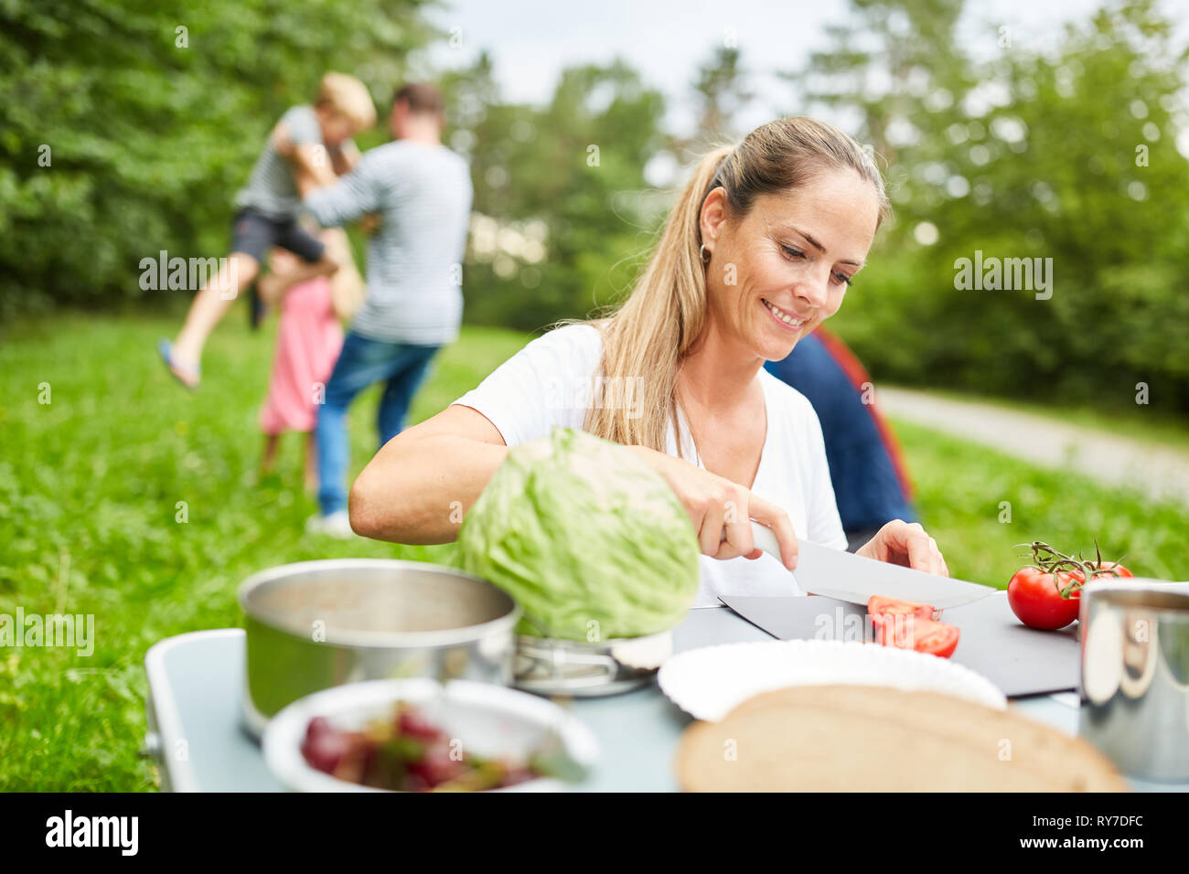 Frau schneidet Gemüse für ein Picknick auf dem Campingplatz in den Sommerferien Stockfoto