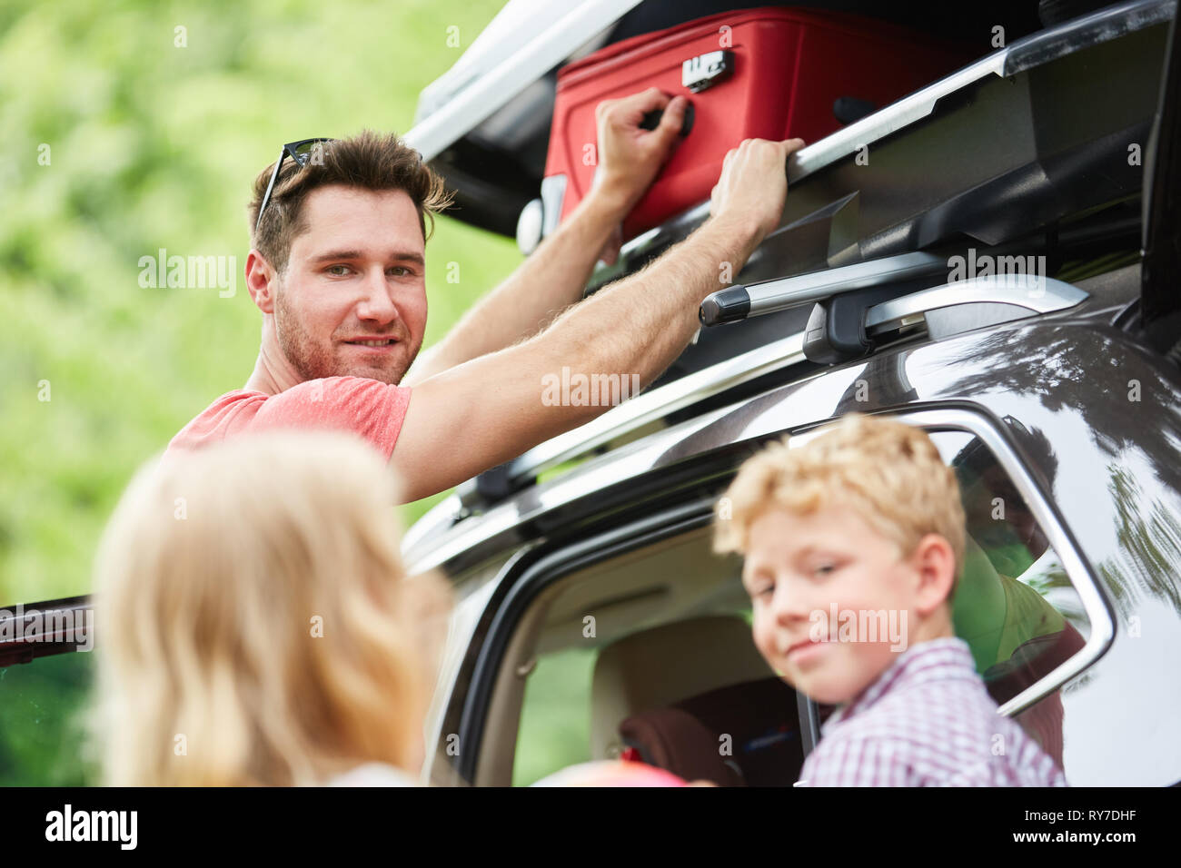 Familie verstaut das Gepäck in die Dachbox auf dem Auto, bevor sie für Ferienhäuser Stockfoto