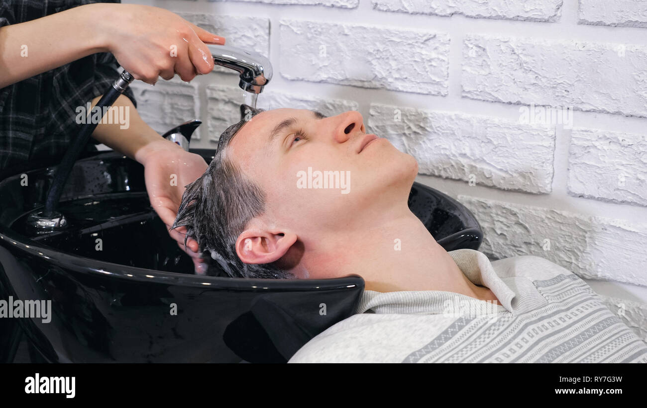 Weibliche Friseur wäscht ein Kopf Mann im barbershop Stockfoto