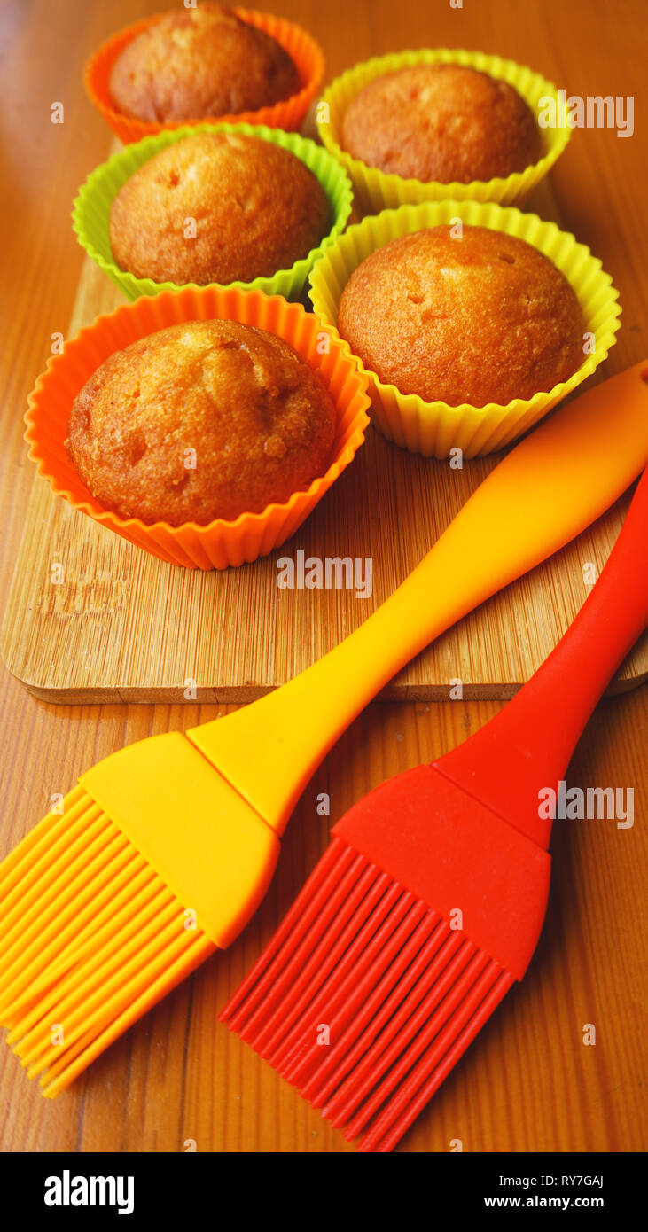 Einfachen mini Muffins in bunten Silikon Backformen. Silikon cup baking Cupcakes und Silikon Pinsel. Küche und kochen Konzept auf hölzernen Hintergrund Stockfoto