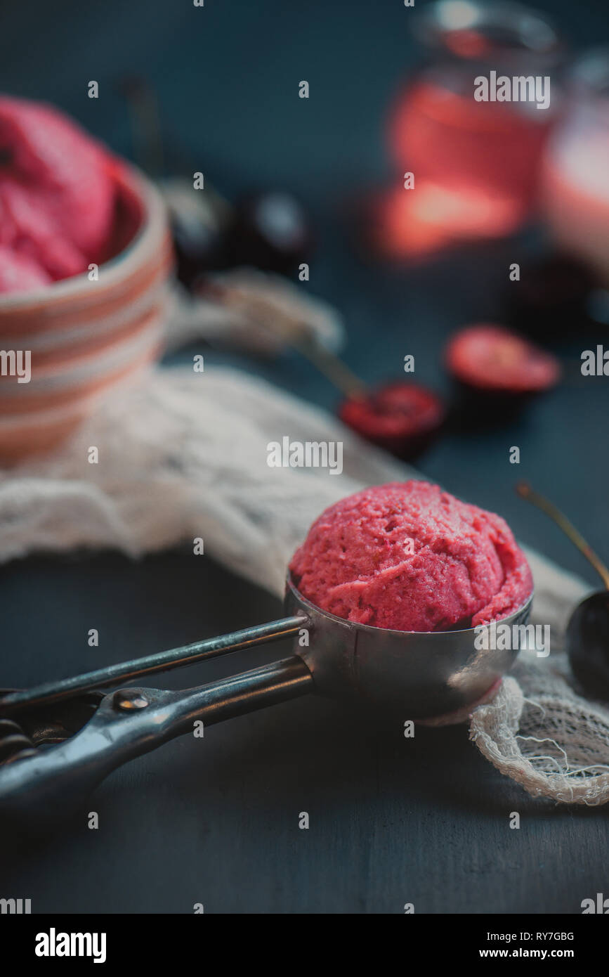 Hausgemachte rosa Eis in Eis Löffel mit Kirschen und Pflaumen. Dunkle essen Fotografie mit Kopie Raum Stockfoto