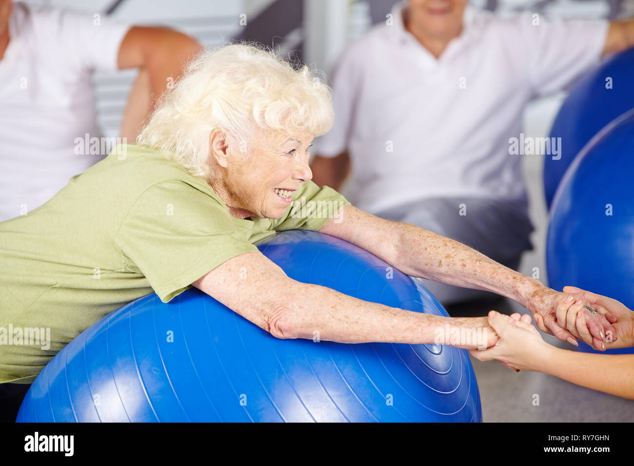 Lächelnd senior Frau tut Fitness im rehab mit Gymnastikball Stockfoto