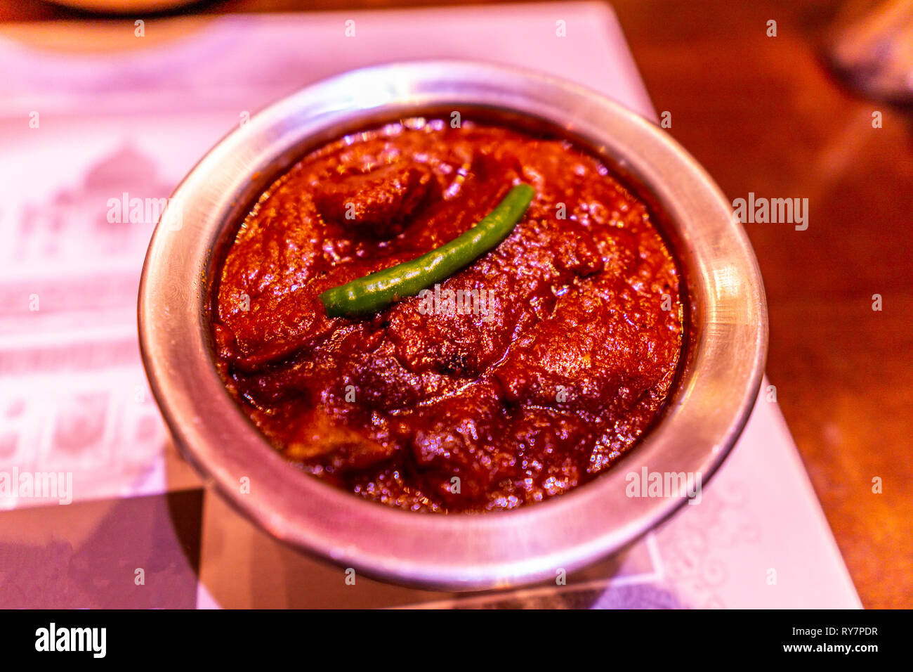 Traditionelles indisches rot gefärbten Vindaloo Lamm Curry in eine Schale mit grünem Chili Detailansicht Stockfoto