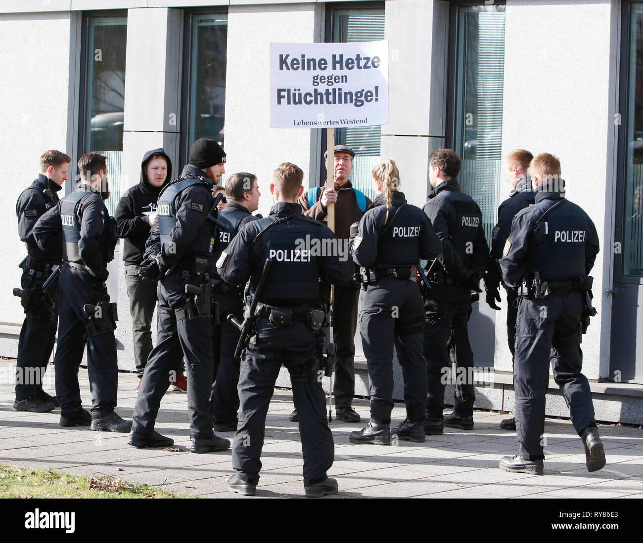 Wiesbaden, Deutschland. 12 Mär, 2019. Einen einzigen Zähler Proteste hält ein Schild mit der Aufschrift "Keine demagogische Propaganda gegen Flüchtlinge außerhalb des Court House. Er ist durch mehrere Polizisten umgeben. Die Gerichtsverfahren gegen die irakische Asylbewerber Ali B. für den Mord an Susanna F. aus Mainz war letztes Jahr in Wiesbaden eröffnet. Mehrere rechtsradikale Organisationen ein Protest außerhalb des Court House gegen Flüchtlinge in Deutschland und für härtere Strafen für Flüchtlinge. Quelle: Michael Debets/Pacific Press/Alamy leben Nachrichten Stockfoto