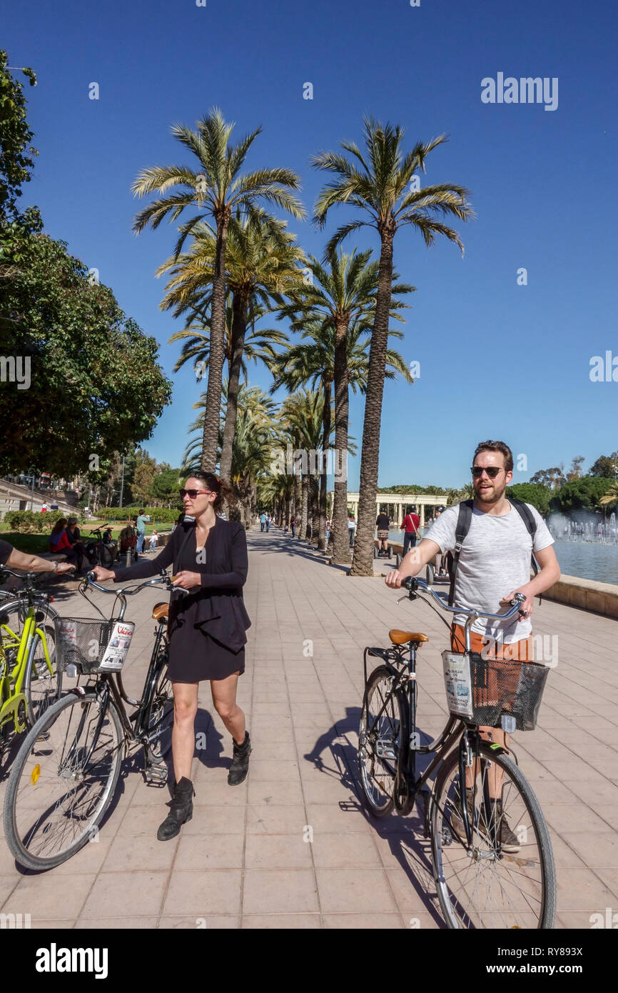 Valencia Turia Park, Leute schieben Fahrräder im Garten mit Palmen, Spanien Fahrrad Stockfoto