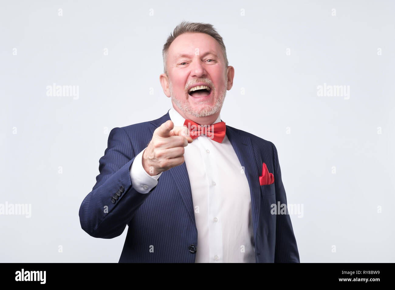 Reifer Mann im blauen Anzug Zeigefinger und toothy Lächeln. Studio shot Stockfoto