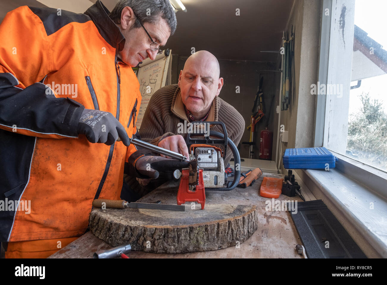 Forstwirtschaft Skills: Menschen, die in einem eintägigen Workshop in, wie man die Schneiden auf die Links einer Kettensäge schärfen, und für die Betreuung sicher und die Power Tool verwenden. Wales UK Stockfoto