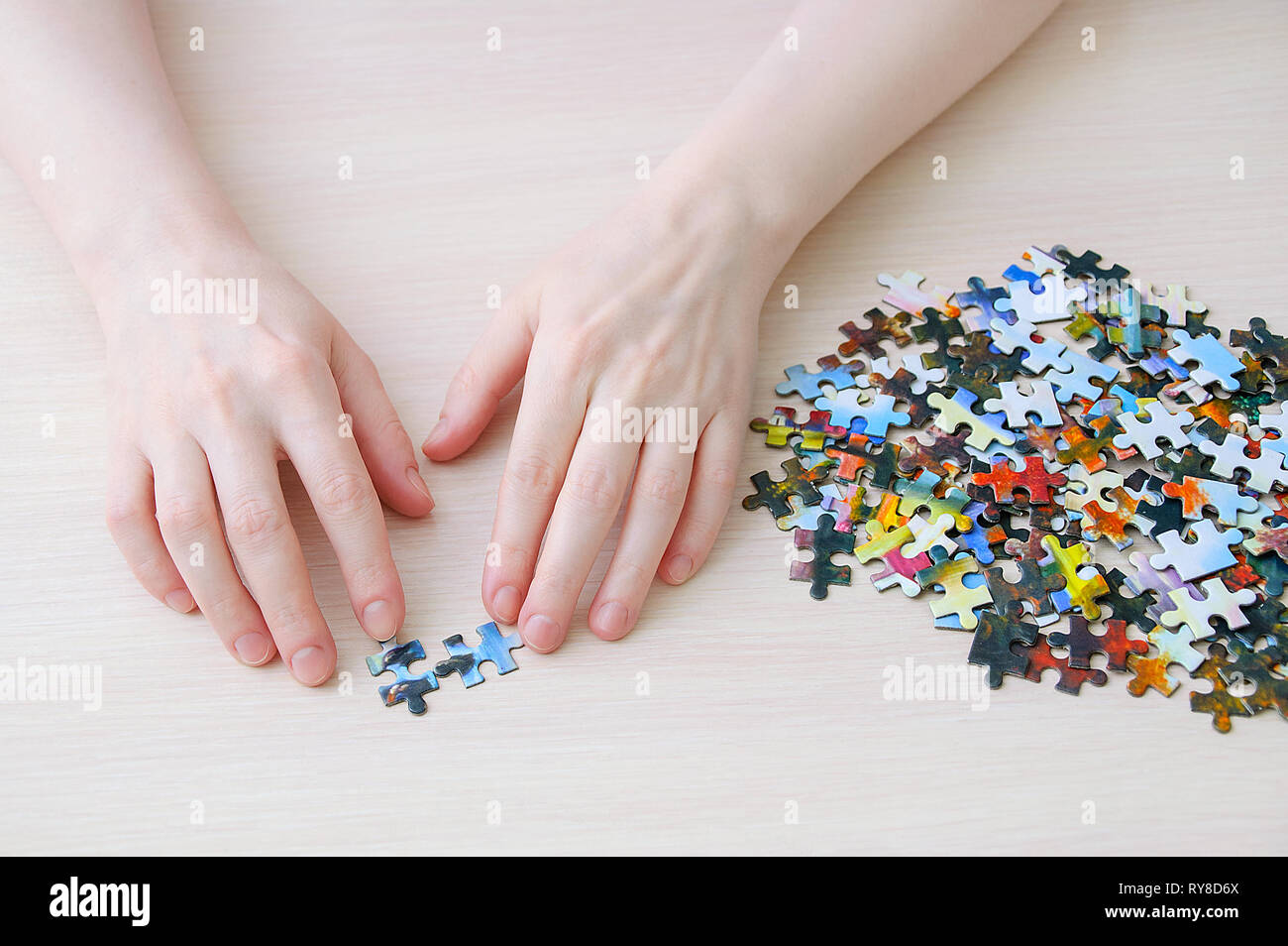 Kaukasische Mädchen sammelt Puzzles auf dem Tisch. Blick von oben. Stockfoto