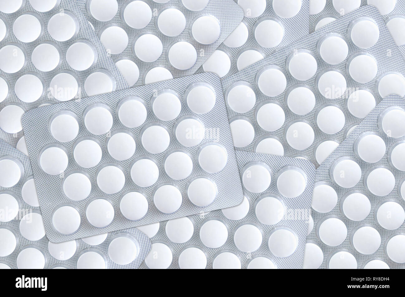 Weiße, runde Tabletten Packungen sind auf der Oberfläche verteilt. Close-up. Stockfoto