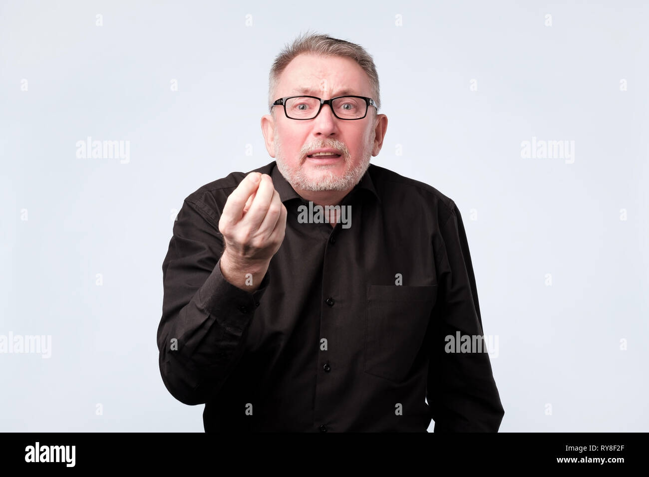 Älterer Mann in Schwarz Shirt, italienische Geste, die bedeutet, was Sie wollen Stockfoto