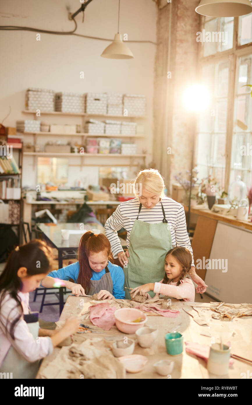 Hohen winkel Porträt der weiblichen Kunst Lehrer, die mit Kindern arbeiten in der Keramik Klasse, Szene beleuchtet durch heitere Sonnenlicht, Kopie Raum Stockfoto