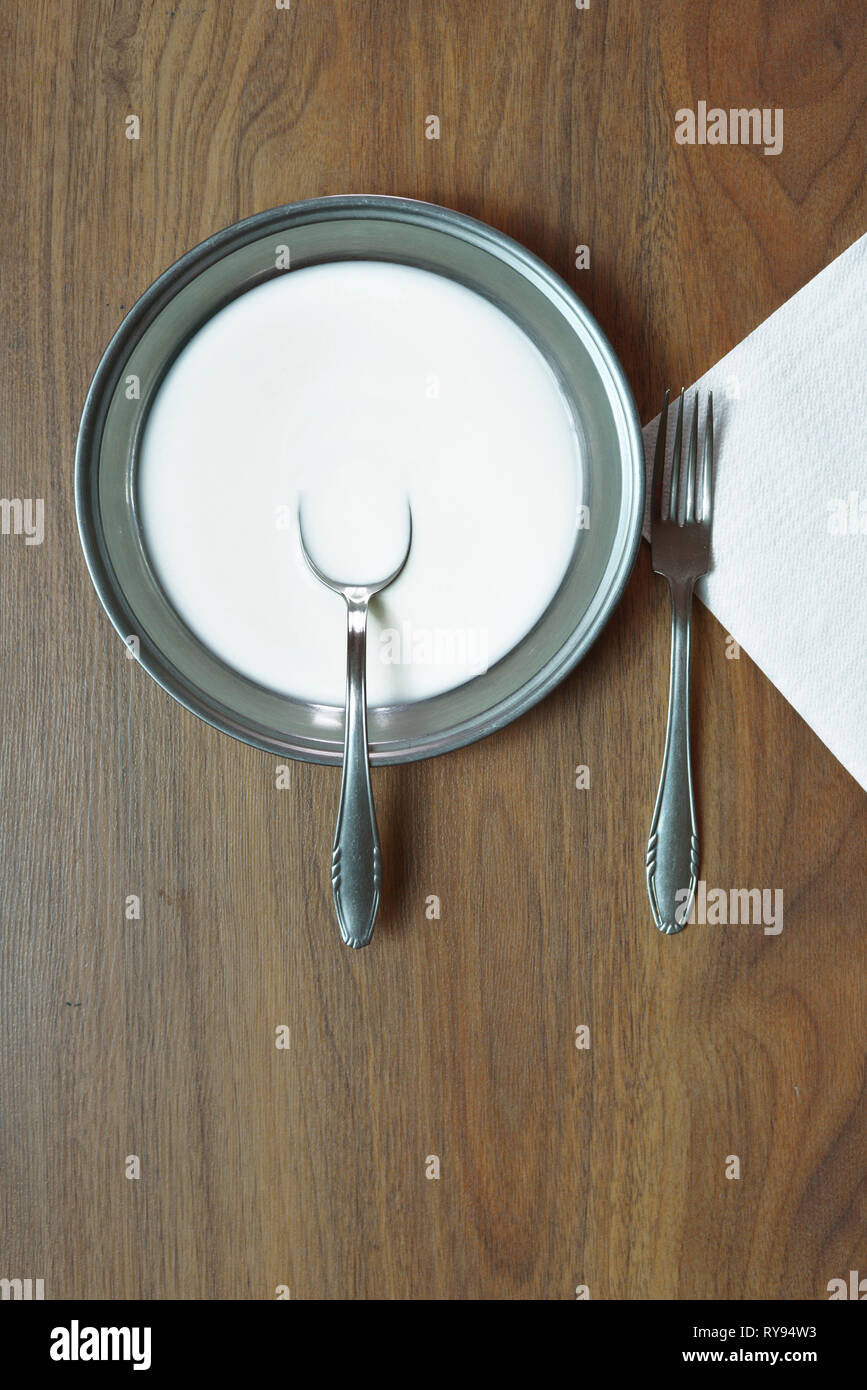 Ansicht von oben von Milch in Teller mit Besteck am Tisch serviert Stockfoto
