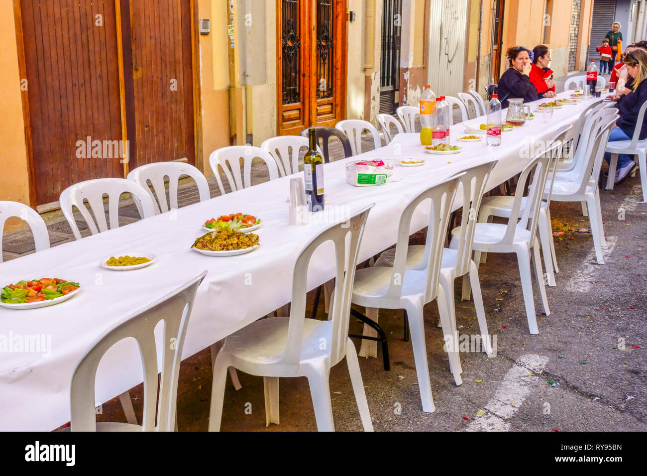 Die Mitglieder von Fallas bereiten Paella auf der Straße zu und essen dann zusammen zu Mittag. Valencia Fallas Party Barrio El Botanico Spanien Mittagessen Stockfoto