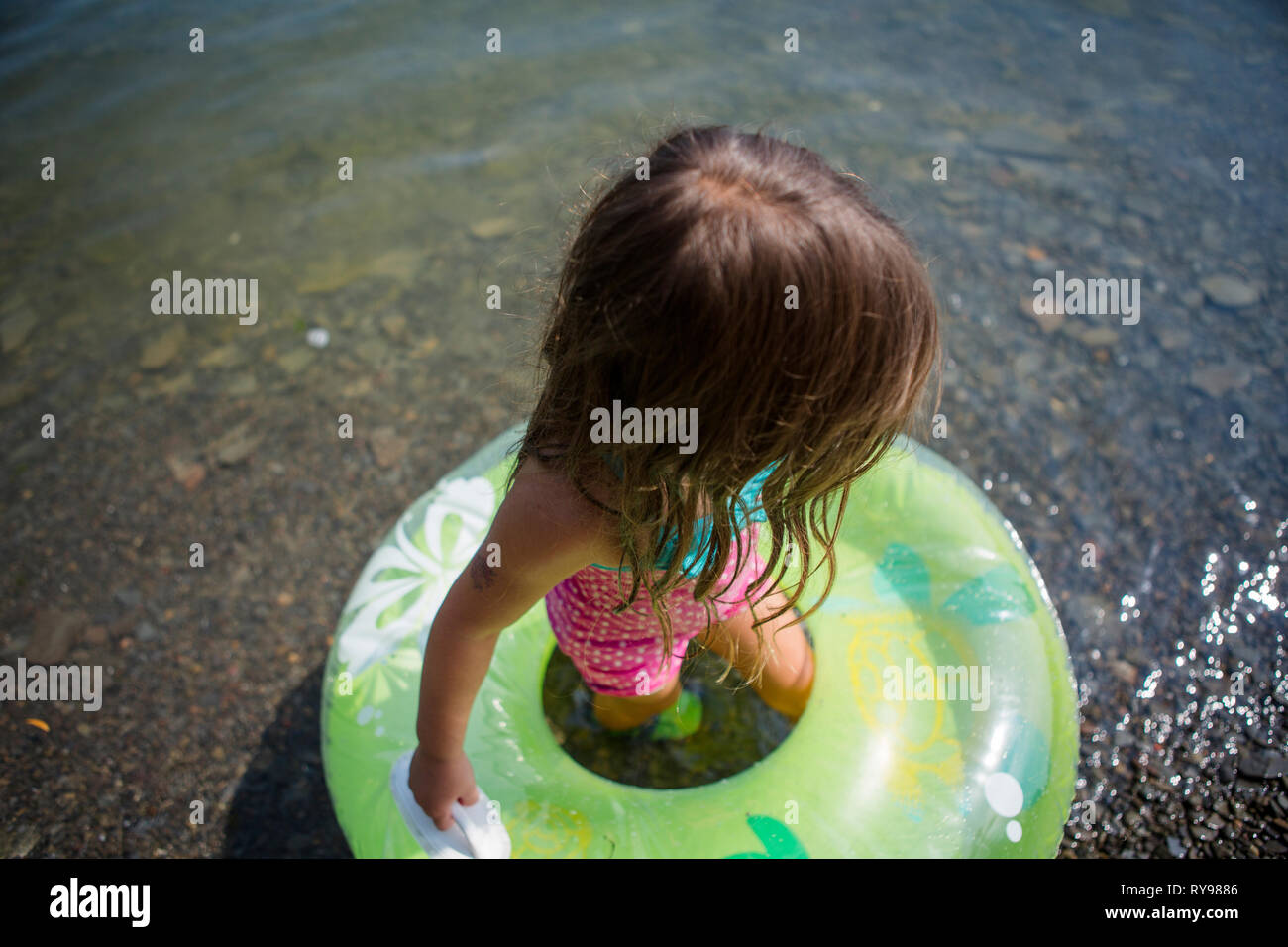 Hohe Betrachtungswinkel von Mädchen mit aufblasbaren Ring in See während der sonnigen Tag Stockfoto