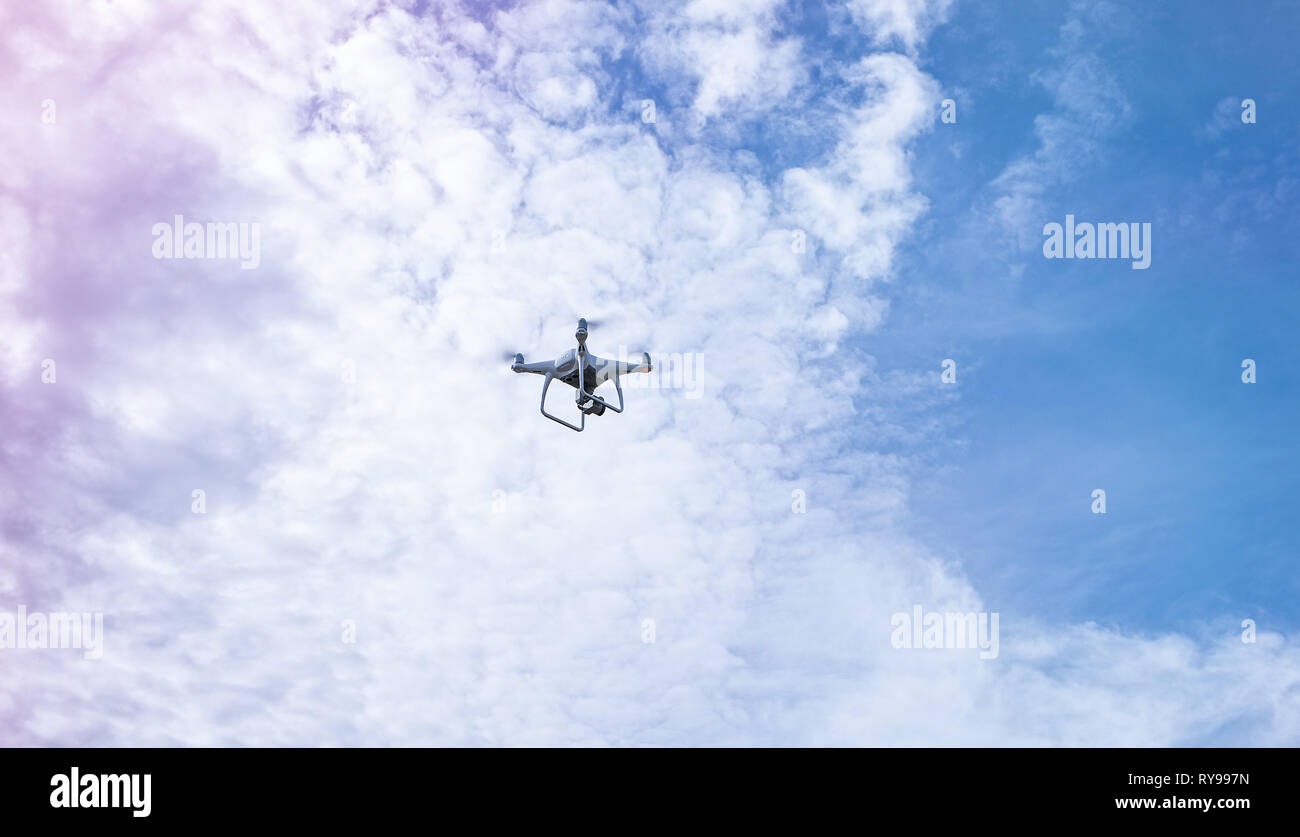 Weiß Drone Quadcopter in der Luft fliegen auf blauen Himmel mit Wolken Stockfoto